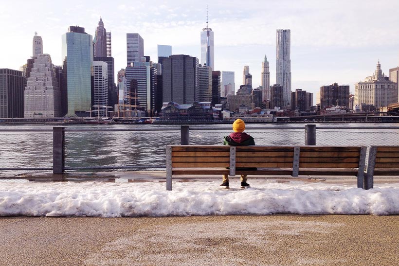 A Lonley Person Is Sitting On A Bench By A River