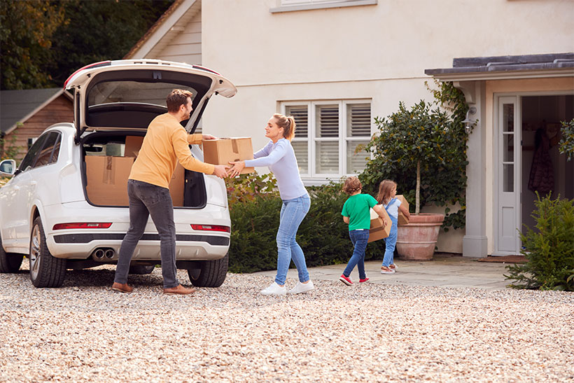 A man and wife are packing small boxes in a trunk