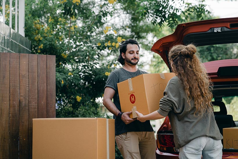 A Couple Is Loading Moving Boxes In Their Car