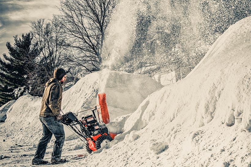 A Man Is Removing The Snow With A Snow Removal Machine