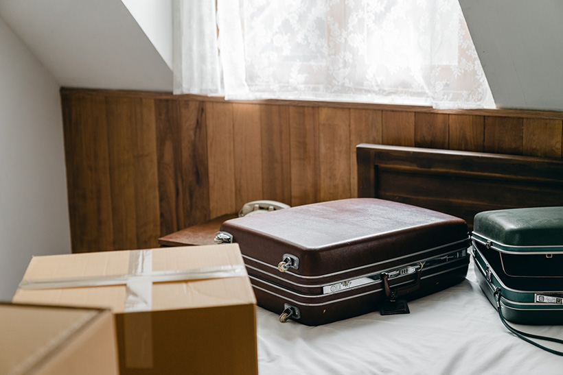 Two Suitcases And A Box On A Bed