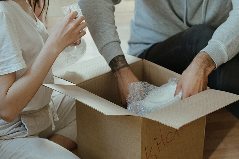 A Couple Is Unpacking Items From A Moving Box