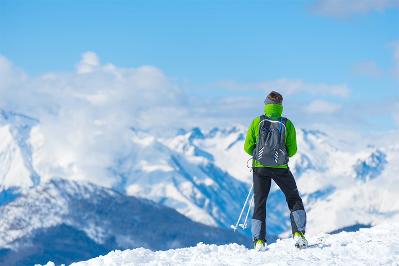 A Skier Standing In The Snow On The Edge Of A Canyon